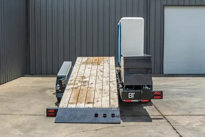 Behnke TBCT2220ET-BT-R trailer, rear view, wood deck, diamond-plate ramp deployed, toolboxes, white cab shield, BT branding visible