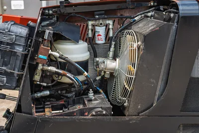 2017 Ditch Witch JT20 open engine compartment showing hydraulic hoses, cooling fan, fluid reservoir, and fuel filter