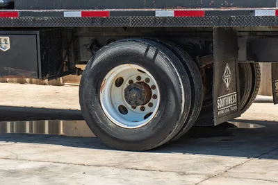 2015 International 7400 mud truck rear axle close-up; Hankook AM09 tire, rusted steel wheel, diamond-plate bed, dual rear tires visible