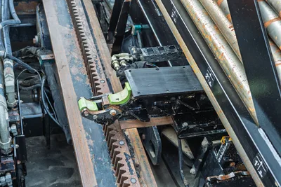 2021 Ditch Witch JT28 drill frame close-up showing rack-and-pinion thrust system, carriage assembly, hydraulic lines, and loaded drill pipe