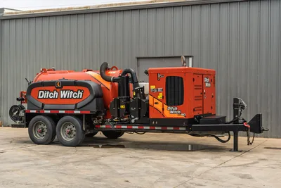 2023 Ditch Witch HX50 hydrovac trailer, driver-side 3/4 view, orange debris tank, vacuum hose, engine enclosure, tandem axle
