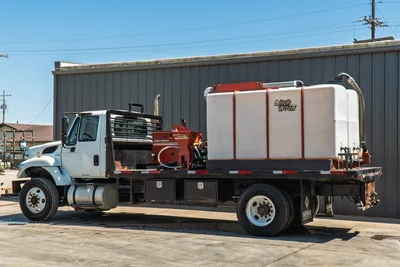 2015 International 7400 flatbed mud truck, driver-side view, Ditch Witch FM13v mixer, large white poly tank, underbody toolboxes