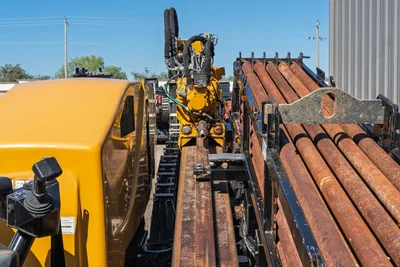 2021 Vermeer D40x55 S3 HDD drill rig rear view showing rack-and-pinion drill frame, spindle, hydraulic lines, and loaded drill pipe rack