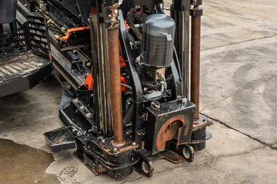 2024 Ditch Witch JT24 drill carriage close-up showing vise assembly, hydraulic cylinder, accumulator, and wear-marked drill frame components.