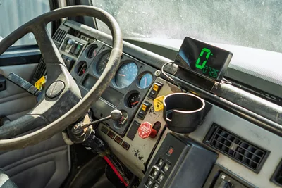 Freightliner FL80 cab interior, steering wheel, analog gauge cluster, and digital display monitor.