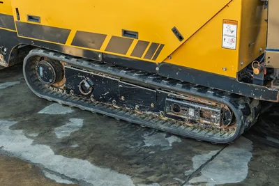 2021 Vermeer D23x30 S3 HDD rig rubber track close-up showing wear, drive sprocket, and yellow chassis with rollover warning decal