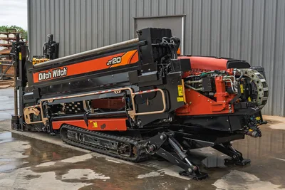 2018 Ditch Witch JT20 horizontal directional drill, side view showing tracks, pipe box, engine compartment, and stabilizers.