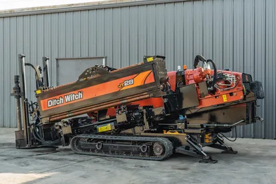 2021 Ditch Witch JT28 HDD drill, 3/4 left rear view, drill frame angled up, loaded drill pipe, rubber tracks, hydraulic components visible