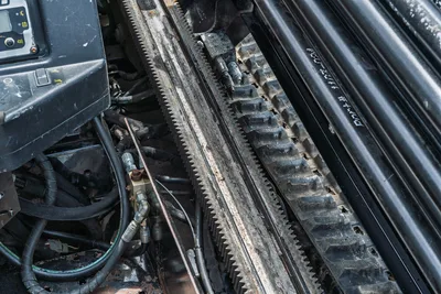 2018 Ditch Witch JT10 drill frame rack-and-pinion thrust system, hydraulic hoses, control panel, and loaded drill pipe closeup