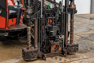 2021 Ditch Witch JT40 rear anchor assembly, close-up of worn stabilizer legs, auger screws, hydraulic lines, and carryall bucket