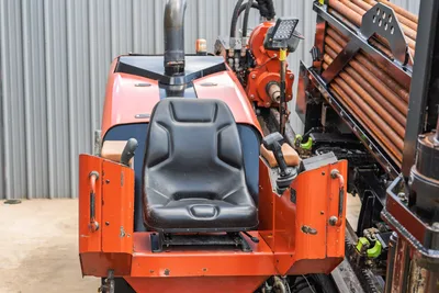 2021 Ditch Witch JT28 operator station, rear view showing seat, joystick controls, loaded drill pipe rack, and carriage assembly