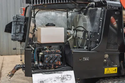 Open engine compartment of 2021 Ditch Witch JT25 showing hydraulic pump, fluid reservoir, cooling fan, and heat shielding.