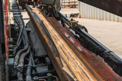 2021 Ditch Witch JT20 drill frame rack-and-pinion carriage track, close-up showing hydraulic lines, vise components, wear from use