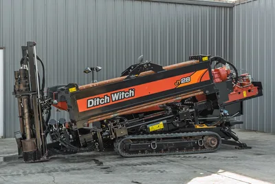 2021 Ditch Witch JT28 HDD drill, driver-side angle, drill frame angled up, drill pipe loaded, rubber tracks, red spindle visible
