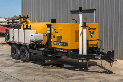 Vermeer LP873SDT trailer-mounted vacuum excavator, 3/4 view, yellow debris tank, engine enclosure, water tanks, dual-axle trailer, tongue with safety chains