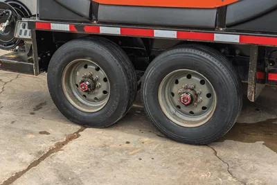 2023 Ditch Witch HX50 mud mixing trailer dual tandem axle wheels, red hub caps, reflective safety striping, black poly tanks visible above frame