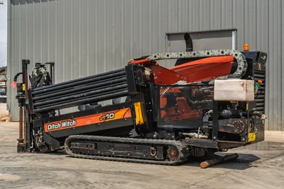 Side view of 2018 Ditch Witch JT10 HDD drill with rubber tracks, pipe rack, and drill string in clean, operating condition.