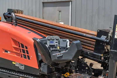 2017 Ditch Witch JT20 operator console with gauges, LCD display, controls, red engine housing, rubber tracks, and loaded drill pipe rack