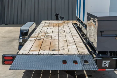 Behnke TBCT2220ET-BT-R trailer wood deck flooring, diamond-plate rear ramp lowered, BT branding, tool boxes, red tail lights visible