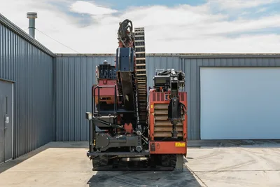 2014 Ditch Witch JT100 Mach 1 HDD drill, rear view, drill frame elevated, rack-and-pinion carriage, hydraulic hoses, rubber tracks visible
