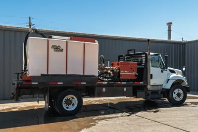 2015 International 7400 mud truck, driver side, flatbed with Ditch Witch FM25 mixer, large white poly tank, mud hoses, manifold plumbing