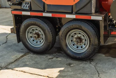 2022 Ditch Witch HX30 mud mixer tandem axle trailer close-up showing dual Radial Trail HD tires, steel wheels, orange frame striping