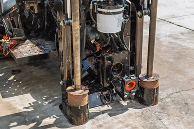 2021 Ditch Witch JT20 front anchor assembly, dual anchor tubes, drill rod visible, hydraulic components, wear-marked steel frame, close-up view