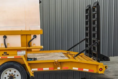 2021 TowMaster T-20D yellow trailer rear deck, raised black loading ramps, poly water tank, wood deck, reflective markers visible