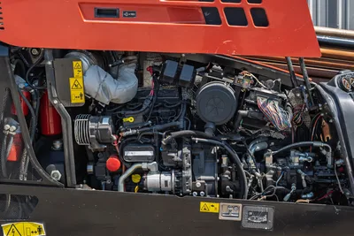 2022 Ditch Witch JT20 engine compartment open, showing 74hp motor, hydraulic lines, wiring harness, air filter, and safety labels