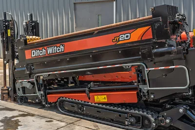 2023 Ditch Witch JT20 HDD drill, side profile showing thrust frame, drill pipe, rubber tracks, hydraulics, and orange carriage assembly