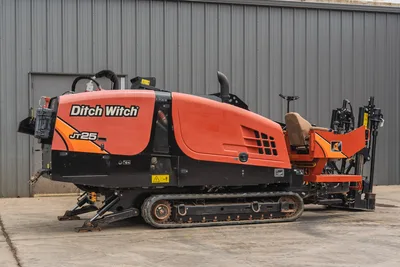 Side view of 2021 Ditch Witch JT25 HDD drill with rubber tracks, operator seat, drill pipe box, and engine compartment.