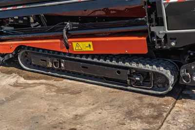 2022 Ditch Witch JT20 rubber track undercarriage, close-up side view showing track drive motor, tie-down points, and electrical hazard warning decal