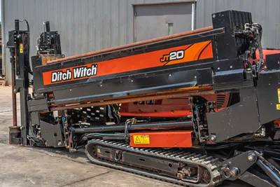 2017 Ditch Witch JT20 HDD rig, side view showing drill frame, rubber tracks, hydraulics, and drill pipe with wear patina