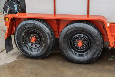 2015 Ditch Witch MR90 mud recycler tandem trailer axle with dual black steel wheels, orange fenders, white tank visible above