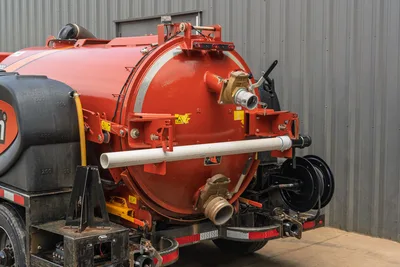 2023 Ditch Witch HX50 rear vacuum tank closeup showing brass fill valve, suction inlet, hose reel, and PVC pipe storage bracket
