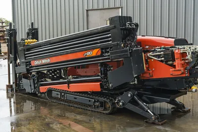 2015 Ditch Witch JT20 HDD drill, angled side view showing loaded drill pipe rack, rubber tracks, hydraulics, and anchor system