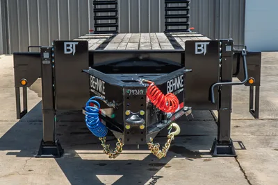 Behnke FB8X30SDPT-40L trailer front coupler, dual air lines, safety chains, hydraulic jacks, wood deck, head-on view.