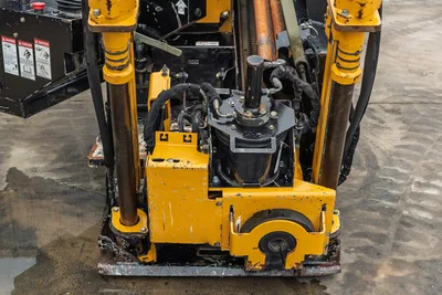2018 Vermeer D8x12 HDD drill head close-up showing rotary drive, thrust frame, hydraulic hoses, and wear-worn yellow carriage