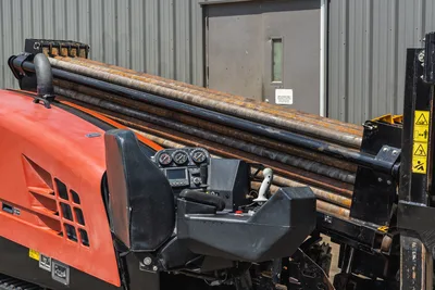 2021 Ditch Witch JT20 HDD drill operator station with gauges, joystick controls, seat, and loaded drill pipe rack visible