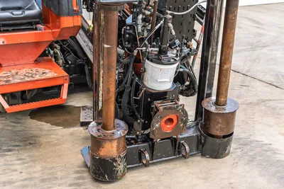 2021 Ditch Witch JT28 rear anchor/thrust frame close-up showing worn anchor posts, hydraulic lines, and drill pipe entry point