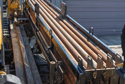 High-angle view of 2009 Vermeer D36x50 Series II pipe rack, drill rods, rack gear, and steel tracks on HDD rig.