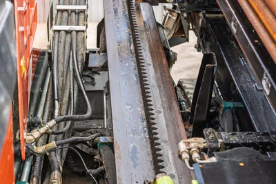 2021 Ditch Witch JT28 thrust rack gear and hydraulic hose bundle, close-up side view showing wear on used drill frame