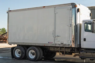 2000 Freightliner FL80 mud truck side profile showing white Morgan box body, dual rear wheels, and chassis detail.