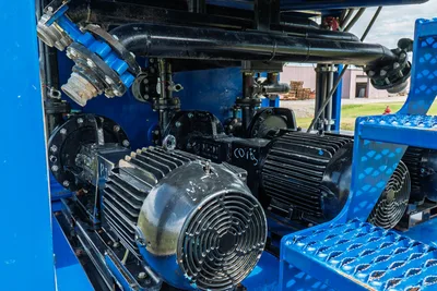 2023 American Augers M300DH mud pump interior: dual electric motors, triplex pump heads, black manifold piping, blue frame, step grating