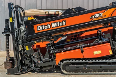 Side profile of 2016 Ditch Witch JT30 All Terrain drill rig showing operator cab, rubber tracks, and drill pipe assembly.