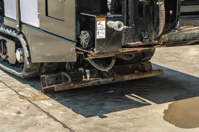 Vermeer 10x15 S3 rear undercarriage detail showing tracked drive system, mud pan, and rotary head connection assembly