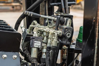 Close-up of Ditch Witch JT20 hydraulic control valve assembly, fittings, and levers from the operator station perspective.