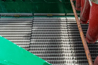 American Augers M300DH shaker screen deck close-up, overhead view showing layered wire mesh panels with green housing and red mud piping