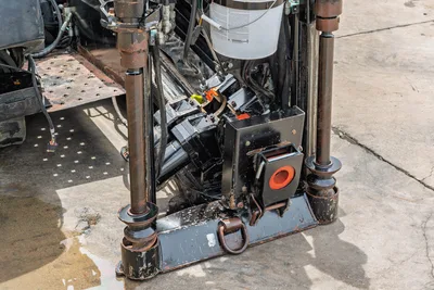 2018 Ditch Witch JT10 drill frame close-up showing vise assembly, drill pipe, hydraulic components, and anchor plate with wear.