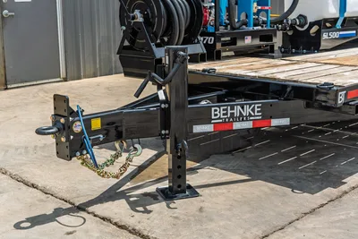 Behnke TBCT2220ET-BT-R trailer tongue close-up showing ball hitch, safety chains, drop-leg jack, and wood-deck flatbed frame